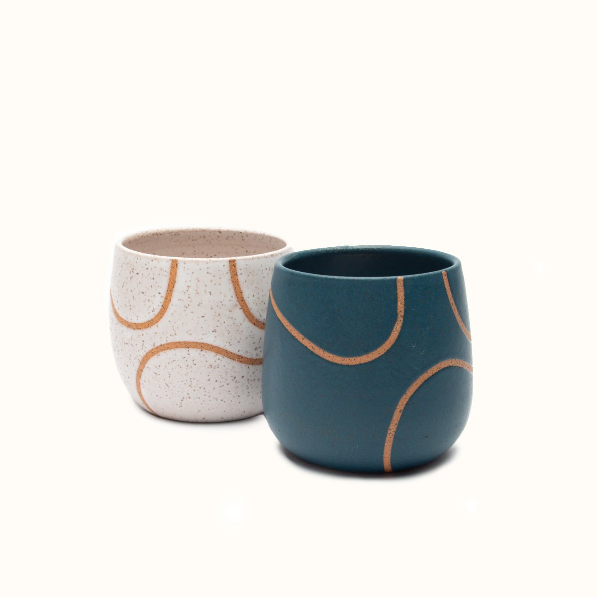 Handless mugs in a matte finish with a single squiggle design in raw speckled clay. From left to right: White, Blue. The Tea Cup with Single Squiggle in White and Blue is designed by Kohai Ceramics and handmade in Portland, OR.