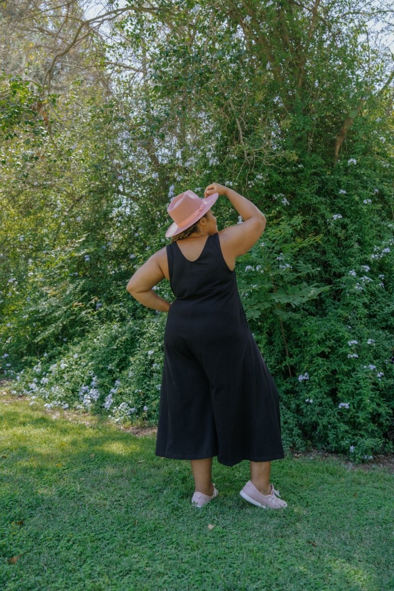 Model shows back side of relaxed sleeveless midi-length jumpsuit with pockets in the color True Black. The Lakeside Jumpsuit is designed by Mien and made in Los Angeles, CA.