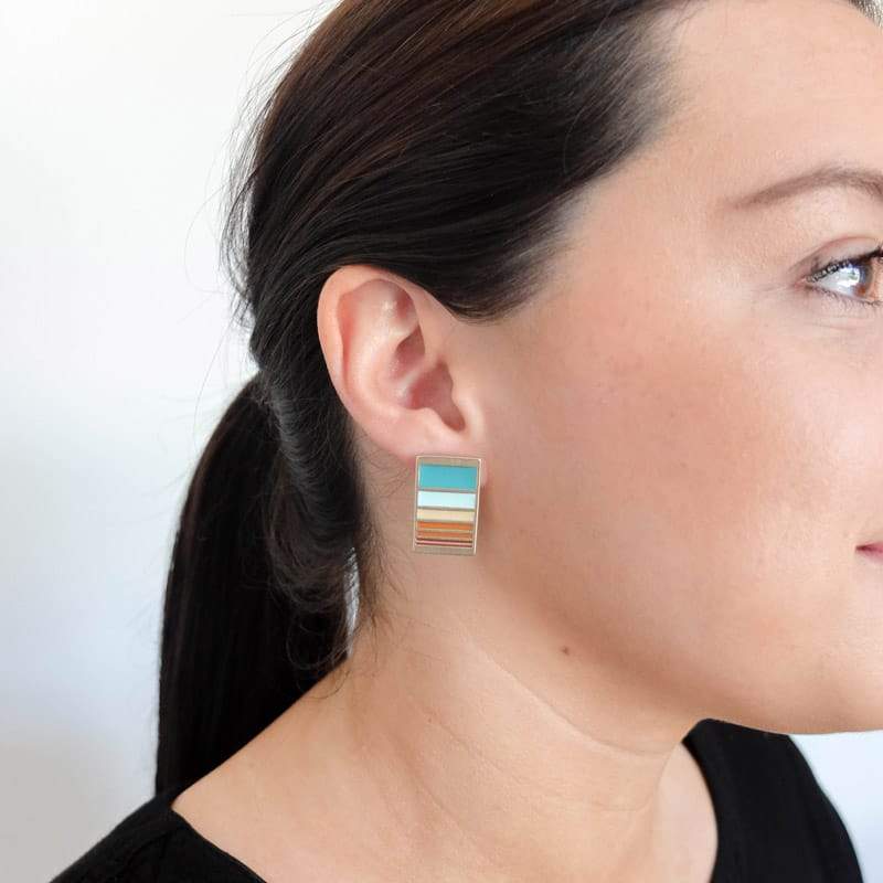 Betsy & iya Lappland stud earrings in the vibrant Mexico colorway, pictured on the profile of a model with dark hair pulled into a ponytail.