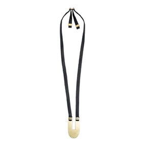 Adjustable, black leather necklace with a sleek, oblong, polished brass statement pendant, brass tubing accents, and an original betsy & iya cast bronze buckle. Hand-crafted in Portland, Oregon.