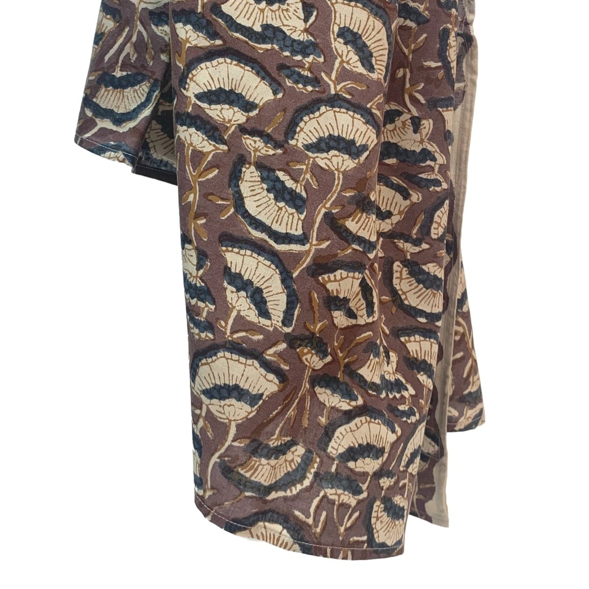 A brown scarf hangs against a white background. The scarf has a floral print pattern in cream and dark grey. The Oversized Scarf in Lena is from designer Maelu.