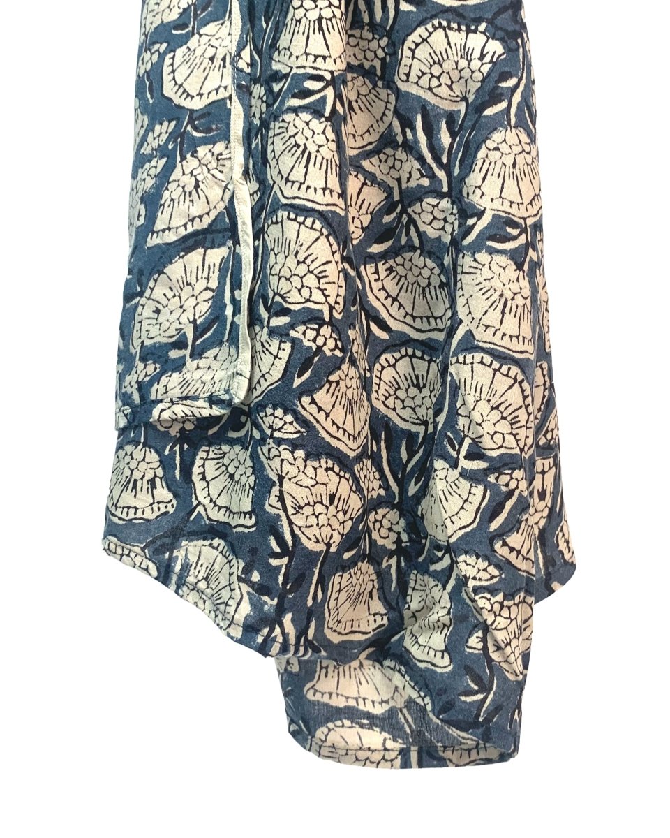 Blue scarf hangs in the air against a white background. The scarf has a cream floral pattern printed on it. The Oversized Scarf in Poppy is from designer Maelu.