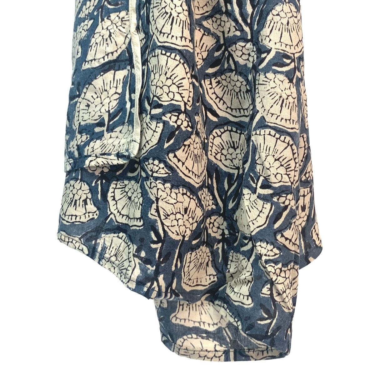 Blue scarf hangs in the air against a white background. The scarf has a cream floral pattern printed on it. The Oversized Scarf in Poppy is from designer Maelu.