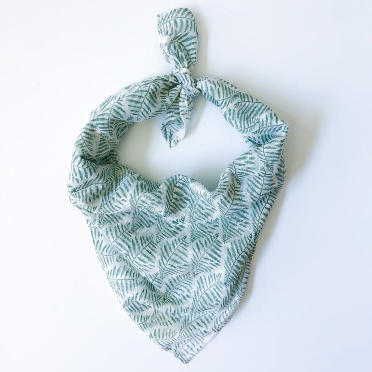 A green and white patterned bandana, folded over and tied in a knot. Block printed by hand, the Laguna Bandana from Maelu is designed in Portland, Oregon and handmade in India.