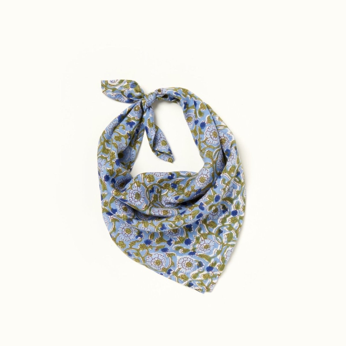 A light blue, dark blue and green floral patterned bandana, folded over and tied in a knot. Block printed by hand, the Alma Bandana from Maelu is designed in Portland, Oregon and handmade in India.