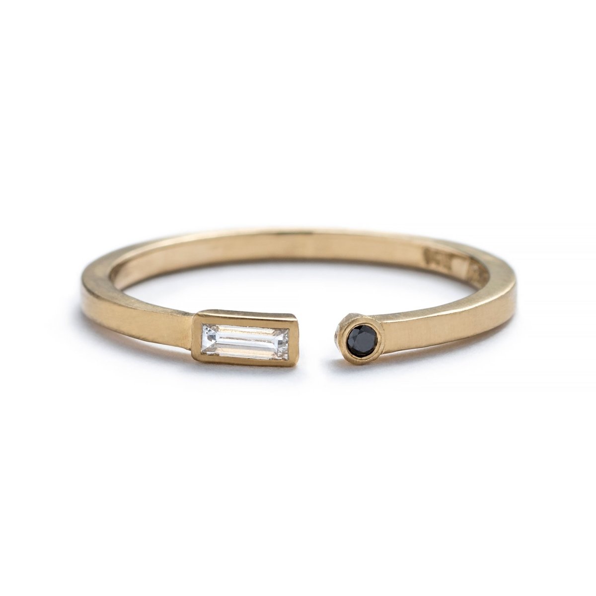 Thin, 14k yellow gold adjustable ring with a matte finish, bezel-set with a small, white diamond baguette on one end, and a small, black, round diamond on the opposite end. Hand-crafted in Portland, Oregon. 