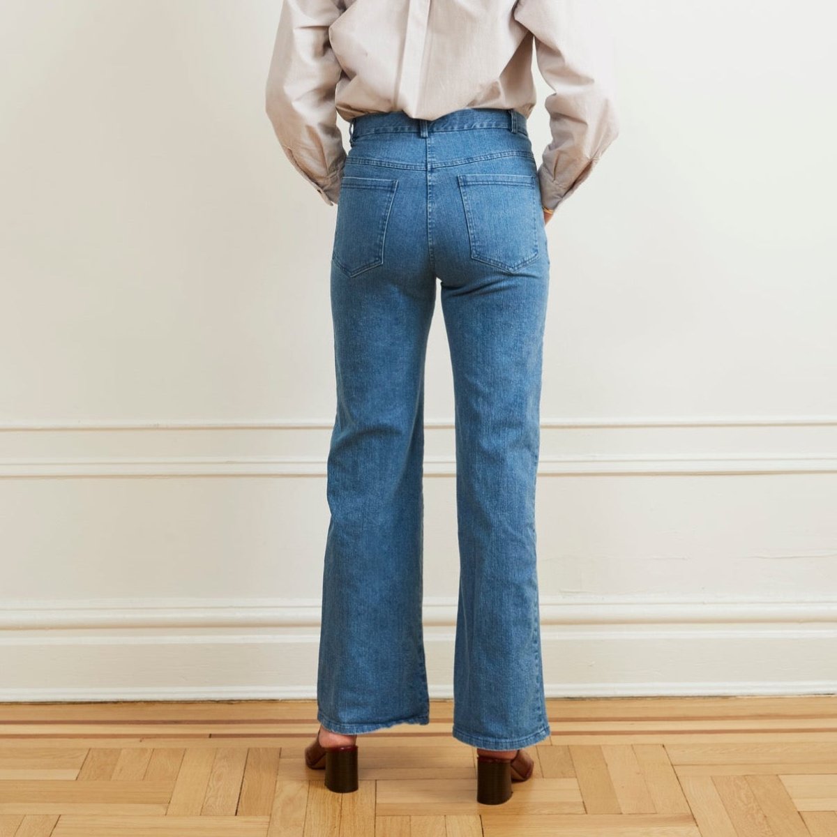 A model shows the backside of a light blue denim jean with a slight boot flare at the bottom. The Marie Jeans in Light Indigo are designed and made by Loup in New York City, USA.
