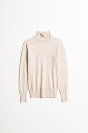 A long sleeve knitted mock neck turtleneck in a cream color. The Merino Turtleneck in Almond White is designed by Dinadi and hand knitted in Kathmandu, Nepal.