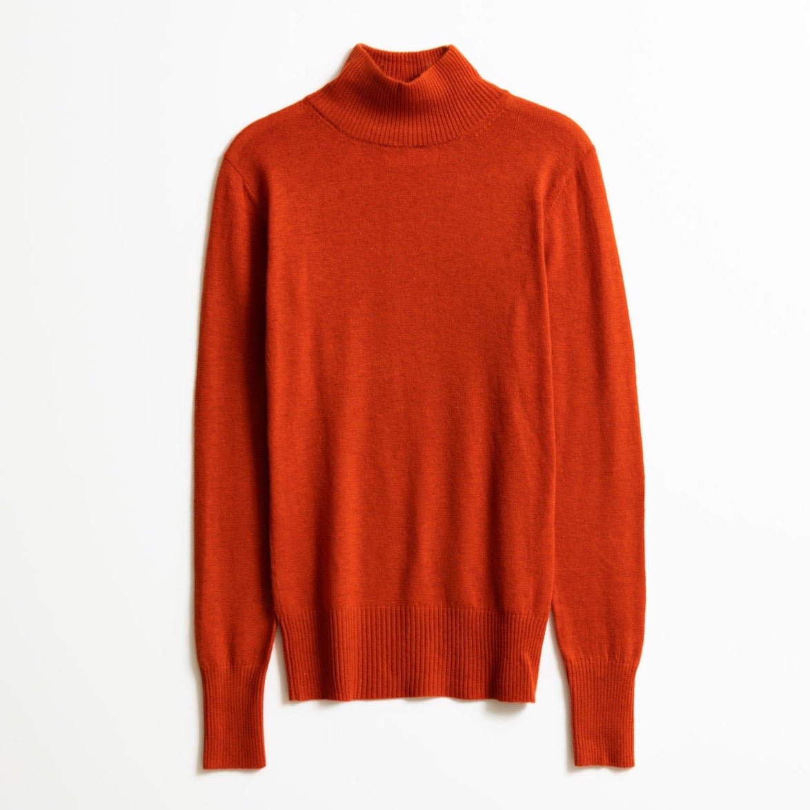 A long sleeve knitted mock neck turtleneck in a bright orange. The Merino Turtleneck in Burnt Orange is designed by Dinadi and hand knitted in Kathmandu, Nepal.
