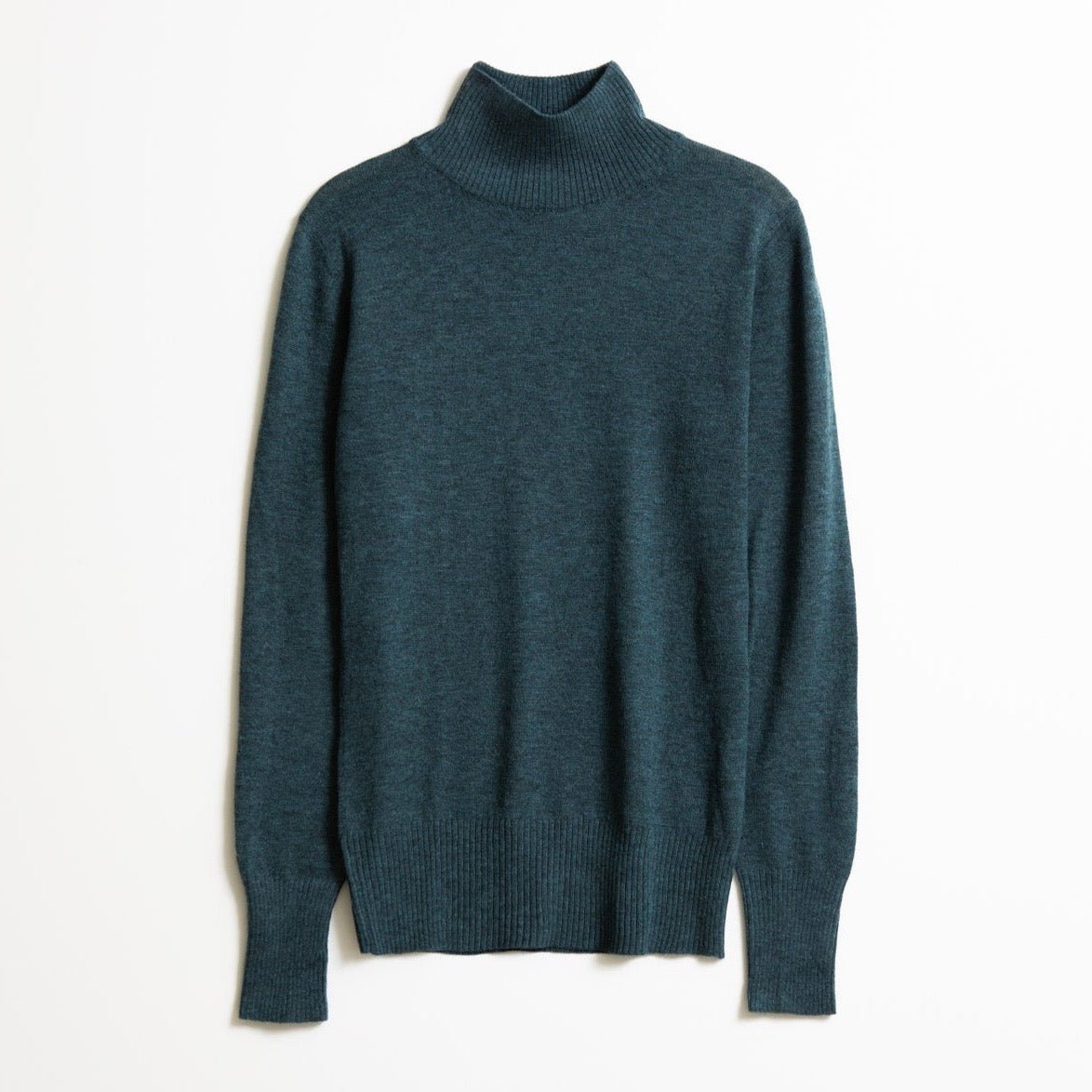 A long sleeve knitted mock neck turtleneck in a dark teal. The Merino Turtleneck in Dragonfly Green is designed by Dinadi and hand knitted in Kathmandu, Nepal.