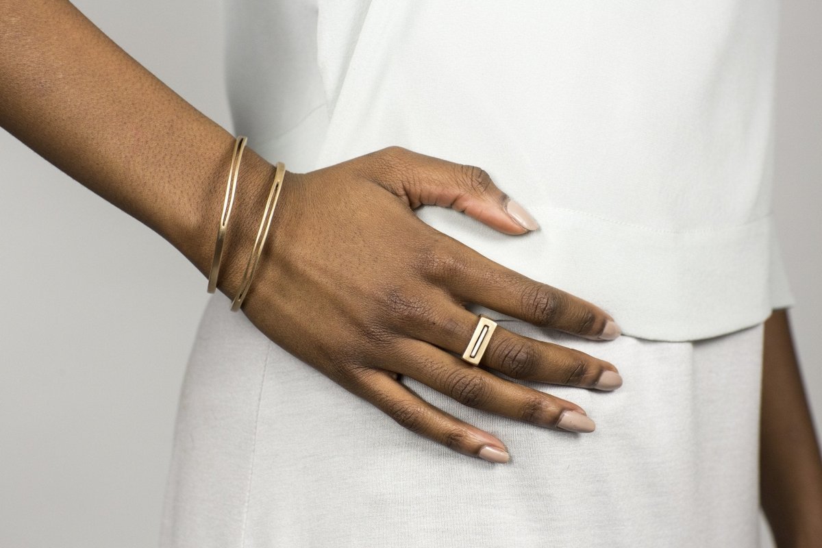 Betsy & iya's Tuyo and Mía rings, fitted together, and worn on a model with a pair of bronze betsy & iya Juntos bangles and an all-white outfit.