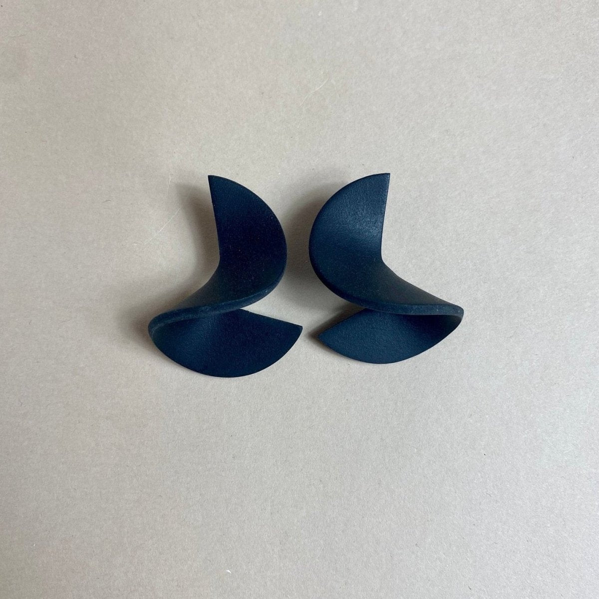 A polymer clay stud earring folded into a small wave. The Modern Crinkle Earrings in Black are designed and handcrafted by Little Pieces Jewelry in Los Angeles, California.