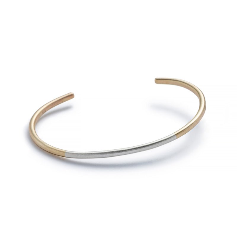 Minimalist, thin, and adjustable stacking cuff of mixed 10k yellow gold and sterling silver hand-forged wire. Hand-crafted in Portland, Oregon.