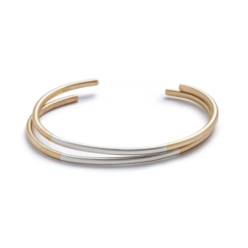 Two minimalist, thin, and adjustable stacking cuffs of mixed 10k yellow gold and sterling silver hand-forged wire. Hand-crafted in Portland, Oregon.