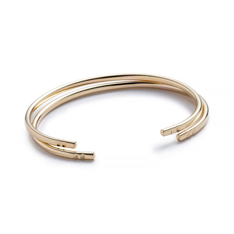 Two minimalist, thin, and adjustable stacking cuffs of 10k yellow gold, with two etched notches on each end. Hand-crafted in Portland, Oregon.
