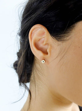 Circular, 14k yellow gold and white diamond betsy & iya Mollis stud earrings, pictured on a model with dark hair.
