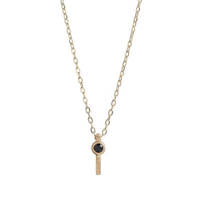 Tiny, ankh-shaped pendant of 14k yellow gold, topped with a round, bezel-set black diamond, and threaded with a delicate gold chain. Hand-crafted in Portland, Oregon.