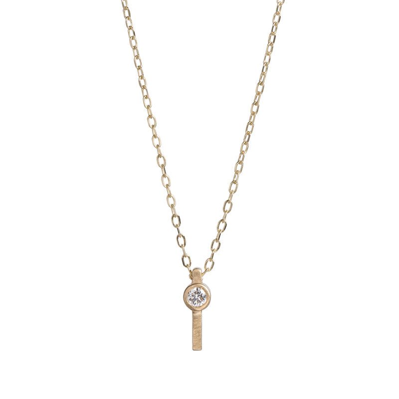 Tiny, ankh-shaped pendant of 14k yellow gold, topped with a round, bezel-set white diamond, and threaded with a delicate gold chain. Hand-crafted in Portland, Oregon.