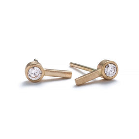 Tiny, ankh-shaped stud earrings of 14k yellow gold, topped with round, bezel-set white diamonds, and finished with 14k gold earring posts. Hand-crafted in Portland, Oregon.