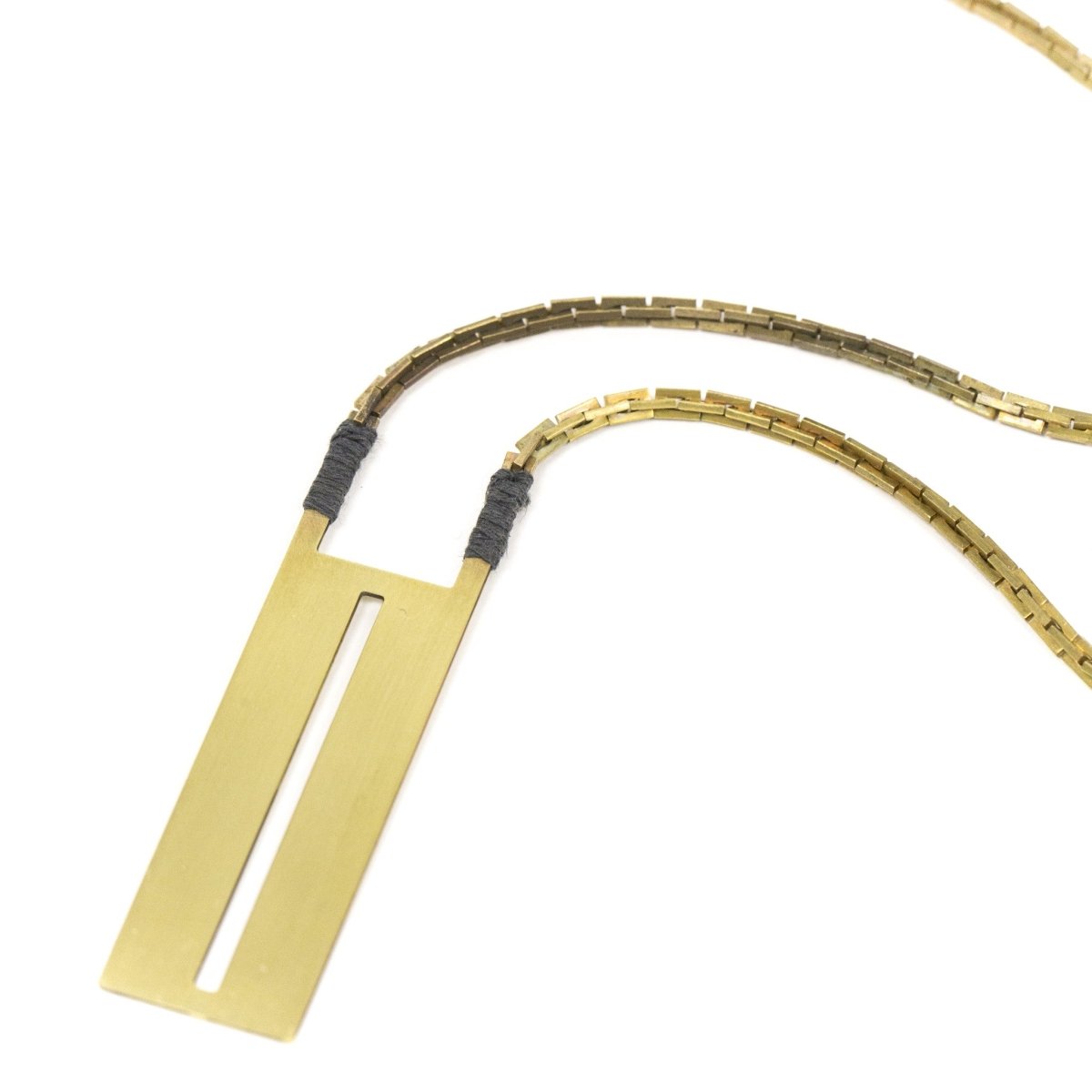 Long statement necklace featuring a vintage deco brass box chain, gray Japanese cotton accents, and a rectangular brass pendant with a thin, slit cutout down the center. Hand-crafted in Portland, Oregon. 