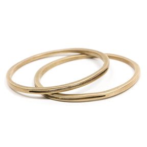 A pair of sturdy, circular, cast-bronze bangle bracelets, each with one long, slim, cutout slit in the metal. Hand-crafted in Portland, Oregon. 