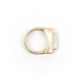 A pair of contemporary rings, featuring one thin, silver ring with an elongated curve fitted through a chunky, bronze ring with a rectangular cutout. Hand-crafted in Portland, Oregon. 