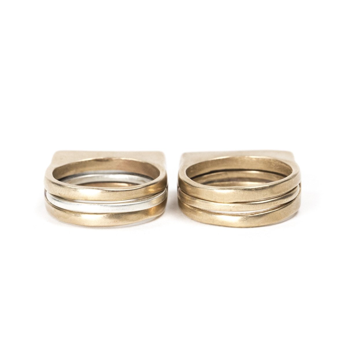 A set of silver and cast bronze Tuyo and Mía rings, and a set of all-bronze Tuyo and Mía rings, pictured side by side. Hand-crafted in Portland, Oregon.