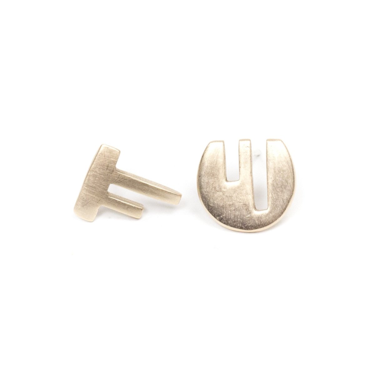 A pair of mismatched, bronze stud earrings, with complementary geometric cutouts that fit into one another like puzzle pieces. Hand-crafted in Portland, Oregon.