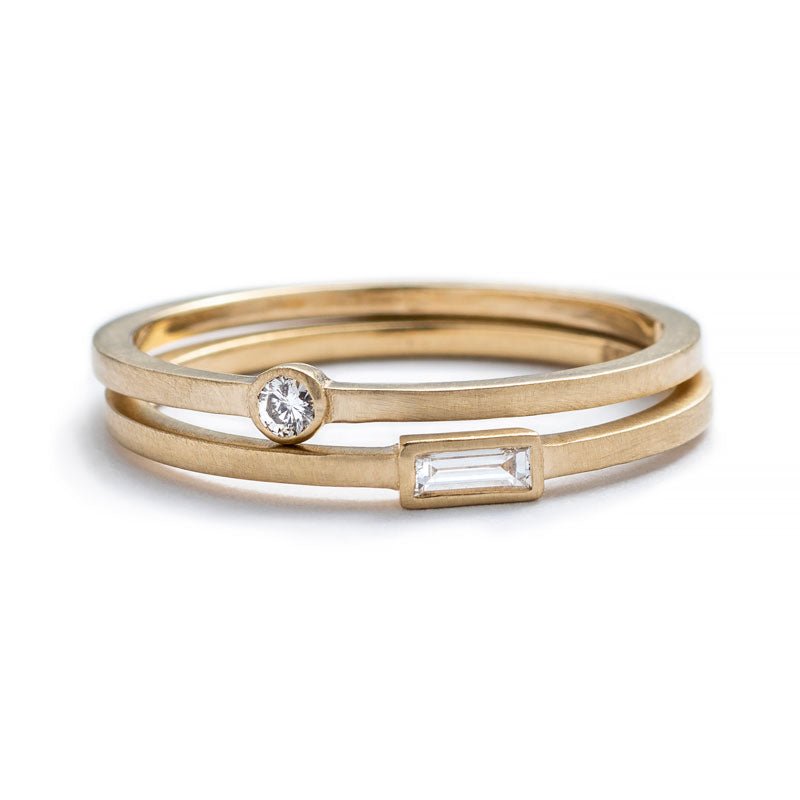 A pair of 14k yellow gold betsy & iya rings: Robur Ring with a small, round, bezel-set white diamond, and Nitor Ring with a bezel-set white diamond baguette. Hand-crafted in Portland, Oregon.