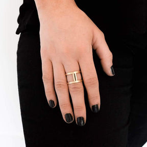 The brass betsy & iya Nous cage ring, in size Short, pictured on the hand of a model with black nail polish.