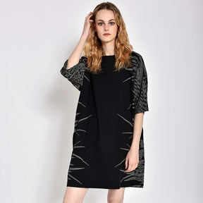 Short black dress with three-quarter sleeves and light grey feather pattern on sides. Designed and sewn by UZI in Brooklyn, New York.