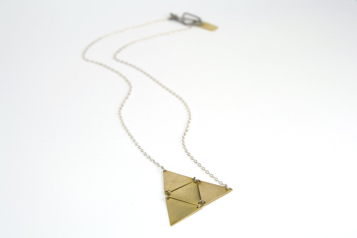 betsy & iya Sandstorm geometric necklace laying casually on a table.