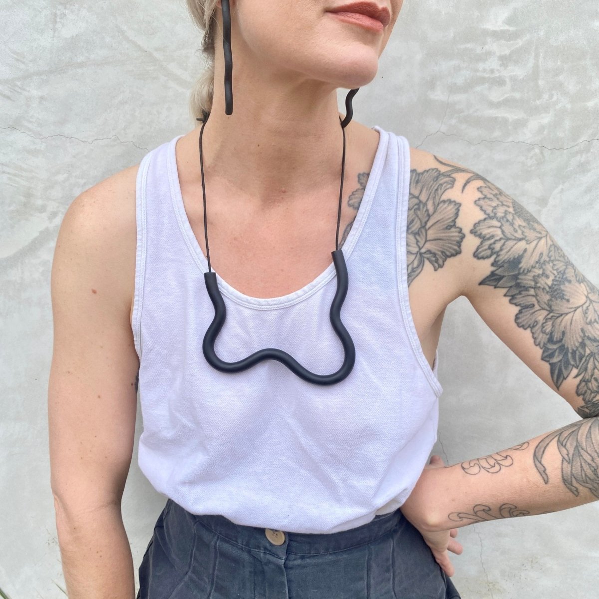 A polymer clay necklace in a wave design with an adjustable leather strap. The Organic Form Necklace in Black is designed and handcrafted by Little Pieces Jewelry in Los Angeles, California.