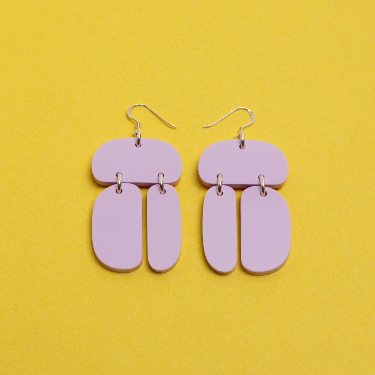 Three softly rounded lilac colored ovoids come together with sterling silver rings and sterling silver ear wires. The Ovoid Trio Earrings in Opaque Lilac are designed and handcrafted  by Warren Steven Scott in Canada.