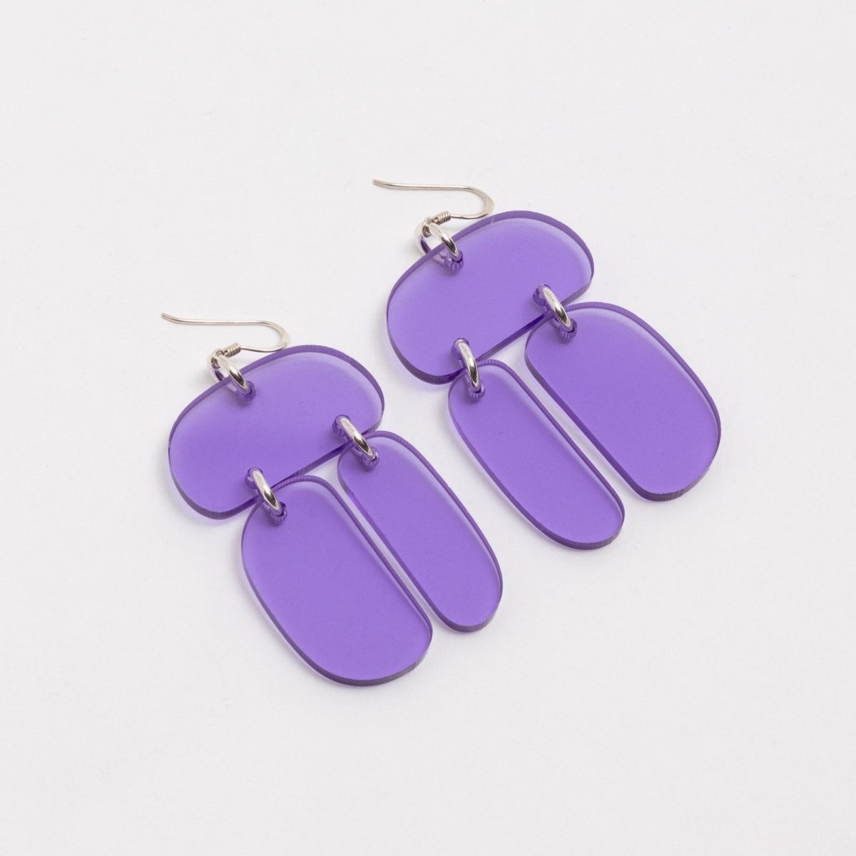 Three softly rounded translucent violet colored ovoids come together with sterling silver rings and sterling silver ear wires. The Ovoid Trio Earrings in Translucent Violet are designed and handcrafted by Warren Steven Scott in Canada.