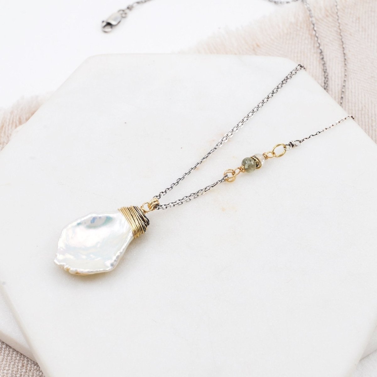 A freshwater pearl pendant hangs from sterling silver chain with aquamarine and citrine accent. The Paige Necklace is designed and handcrafted by Amy Olson in Portland, Oregon.