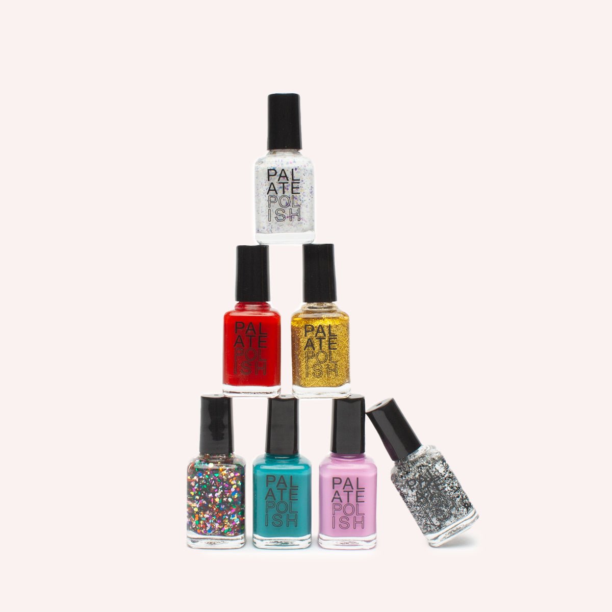 A pyramid of nail polish bottles in various colors. From bottom starting left to right: Gumball, Blue Raspberry, Cherry Blossom, Cookies and Cream, Hot Sauce, Gold Gumdrop, and Jawbreaker. All are vegan and 10-Free (almost non-toxic).
