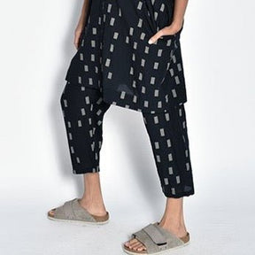 A model wears a loose fitting cropped straight leg black pant with an off-white square pattern. The Pants in Black Disko are designed and sewn by UZI NYC in Brooklyn, New York. 