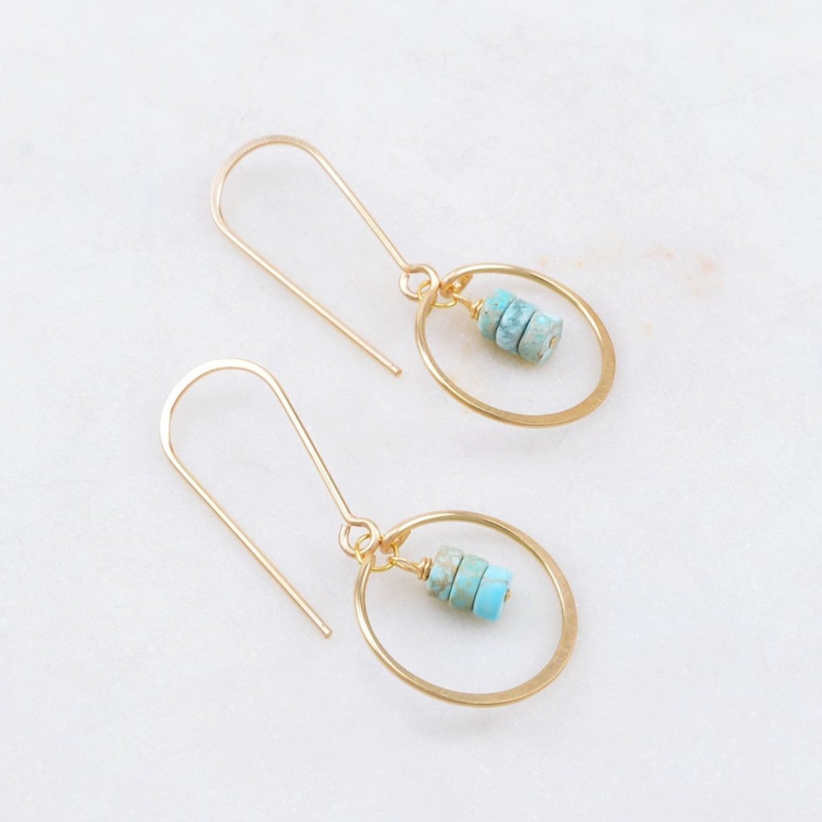 A curved gold-fill ear wire holds a hammered gold-fill circle. Three round turquoise beads hang from the center of the circle. The Petite Gem Drop Earrings in Turquoise are designed and handcrafted by Amy Olson in Portland, Oregon.