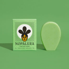 An oval shaped green bar soap stands to the right of its green rectangular packaging. This cactus soap contains  a subtle scent of eucalyptus, lemongrass and sage oil. The Planta Futura Cactus Soap is from Nopalera and made in Brooklyn, NY.