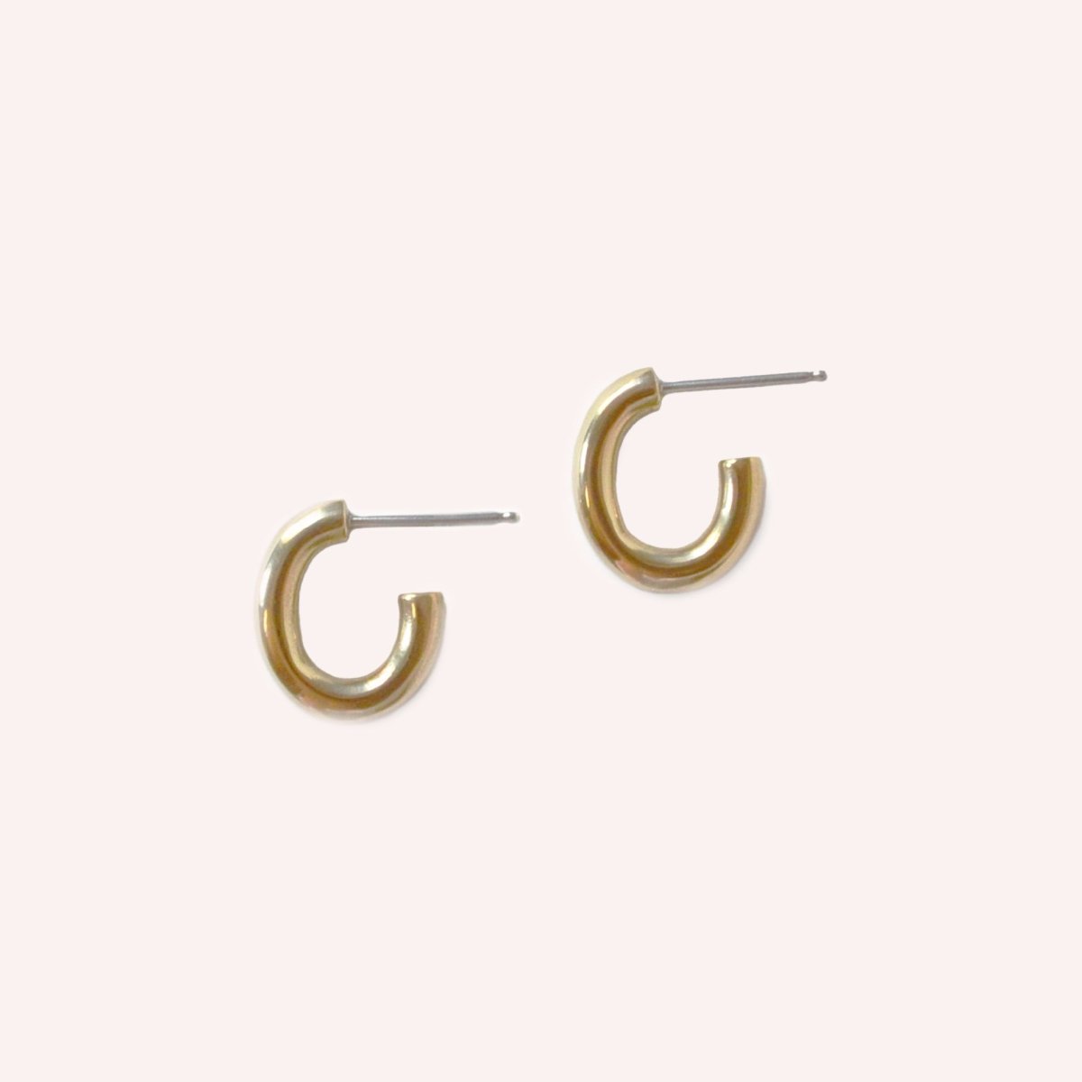 A smooth gold tone oval shaped hoop with sterling silver earring posts. The Pool Hoops in Brass are designed and handcrafted by Natalie Joy in Portland, Oregon.