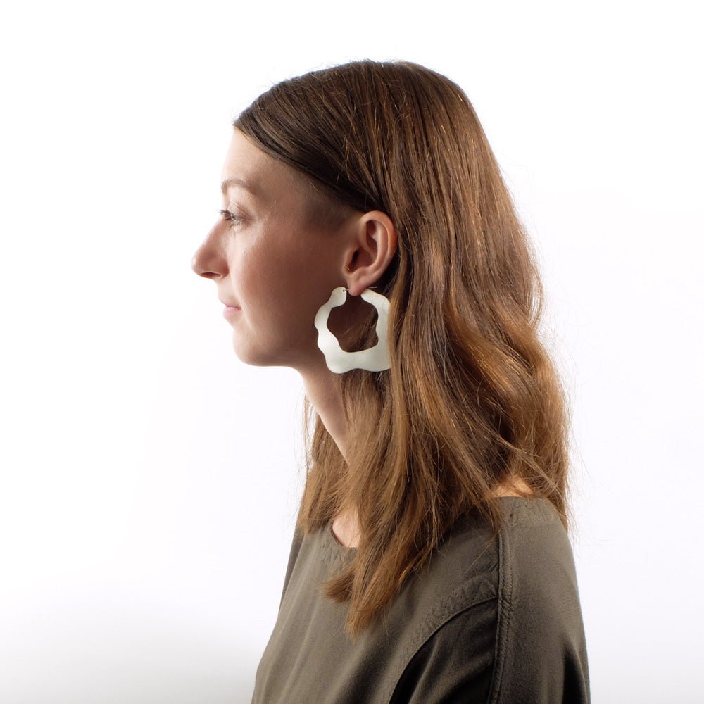 Betsy & iya statement Villo hoop earrings in brushed sterling silver, pictured on the profile of a model with long, golden brown hair.