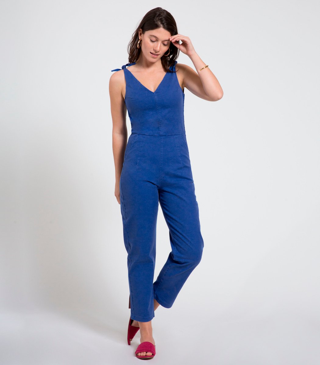 Model wears a bright blue colored jumpsuit with a V-neckline and tie up shoulder straps. The Slate Overalls in Royal are designed by Loup and made in New York City, USA.