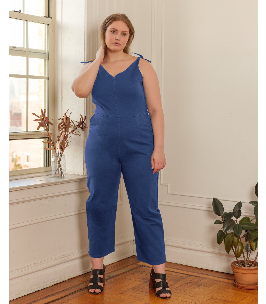 Model wears a bright blue colored jumpsuit with a V-neckline and tie up shoulder straps. The Slate Overalls in Royal are designed by Loup and made in New York City, USA.