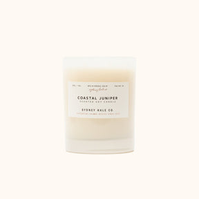  A cylindrical glass candle filled with a soy wax blend and two double cotton wicks. Label reads: "397g/14 oz. Manufactured in Virginia, USA by Sydney Hale Co. Coastal Juniper scented soy candle. Sydney Hale Co. Supporting Animal rescue since 2010."