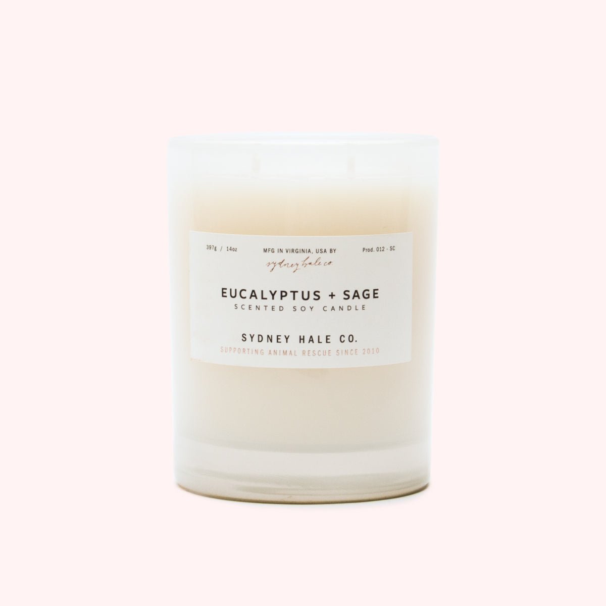 A cylindrical glass candle filled with a soy wax blend and two double cotton wicks. Label reads: "397g/14 oz. Manufactured in Virginia, USA by Sydney Hale Co. Eucalyptus + Sage scented soy candle. Sydney Hale Co. Supporting Animal rescue since 2010."