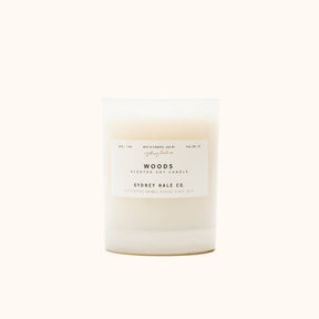 A cylindrical glass candle filled with a soy wax blend and two double cotton wicks. Label reads: "397g/14 oz. Manufactured in Virginia, USA by Sydney Hale Co. Woods scented soy candle. Sydney Hale Co. Supporting Animal rescue since 2010."