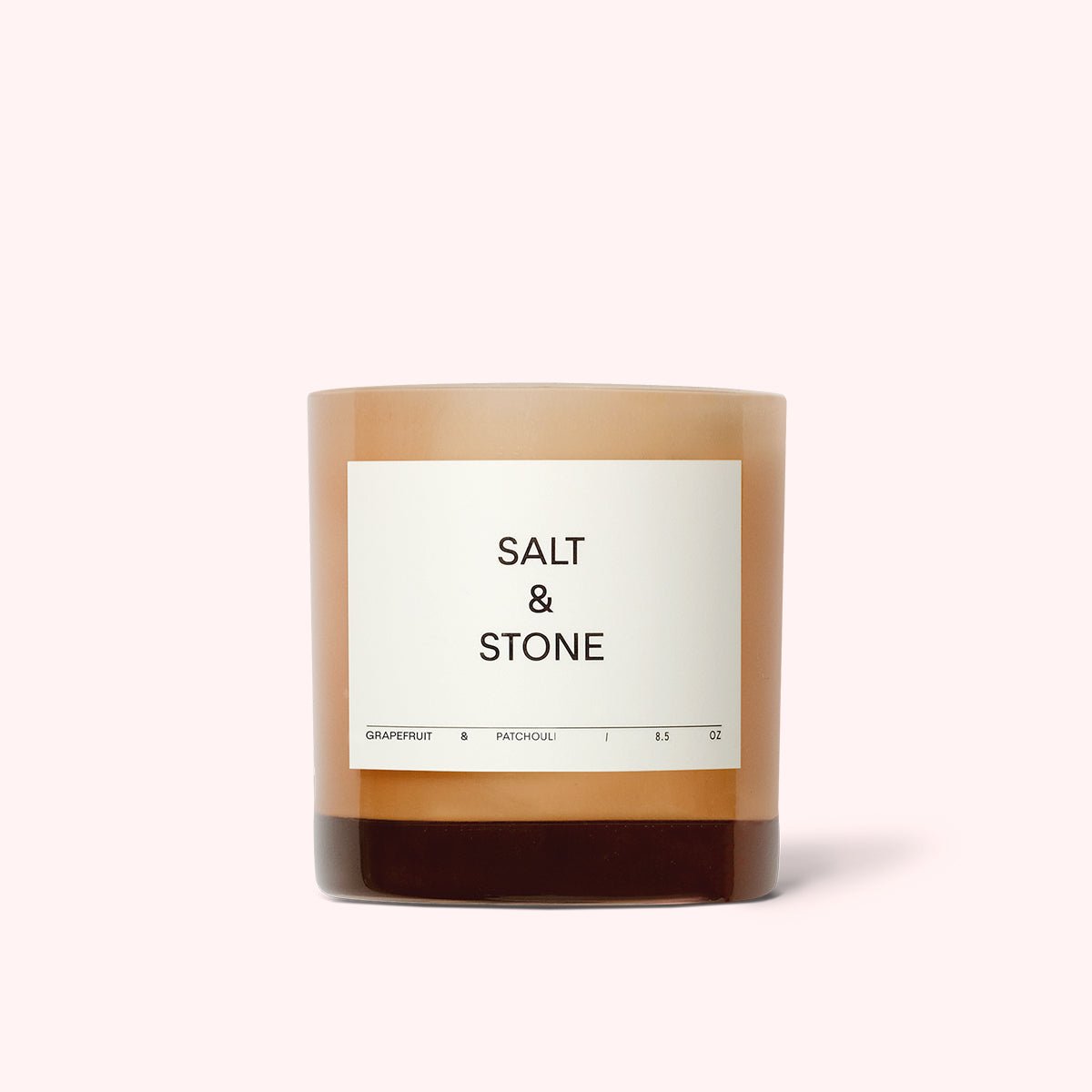 Light pink glass jar filled with a coconut and soy wax candle. The Grapefruit & Patchouli Candle is designed by Salt & Stone and made in Los Angeles, CA.