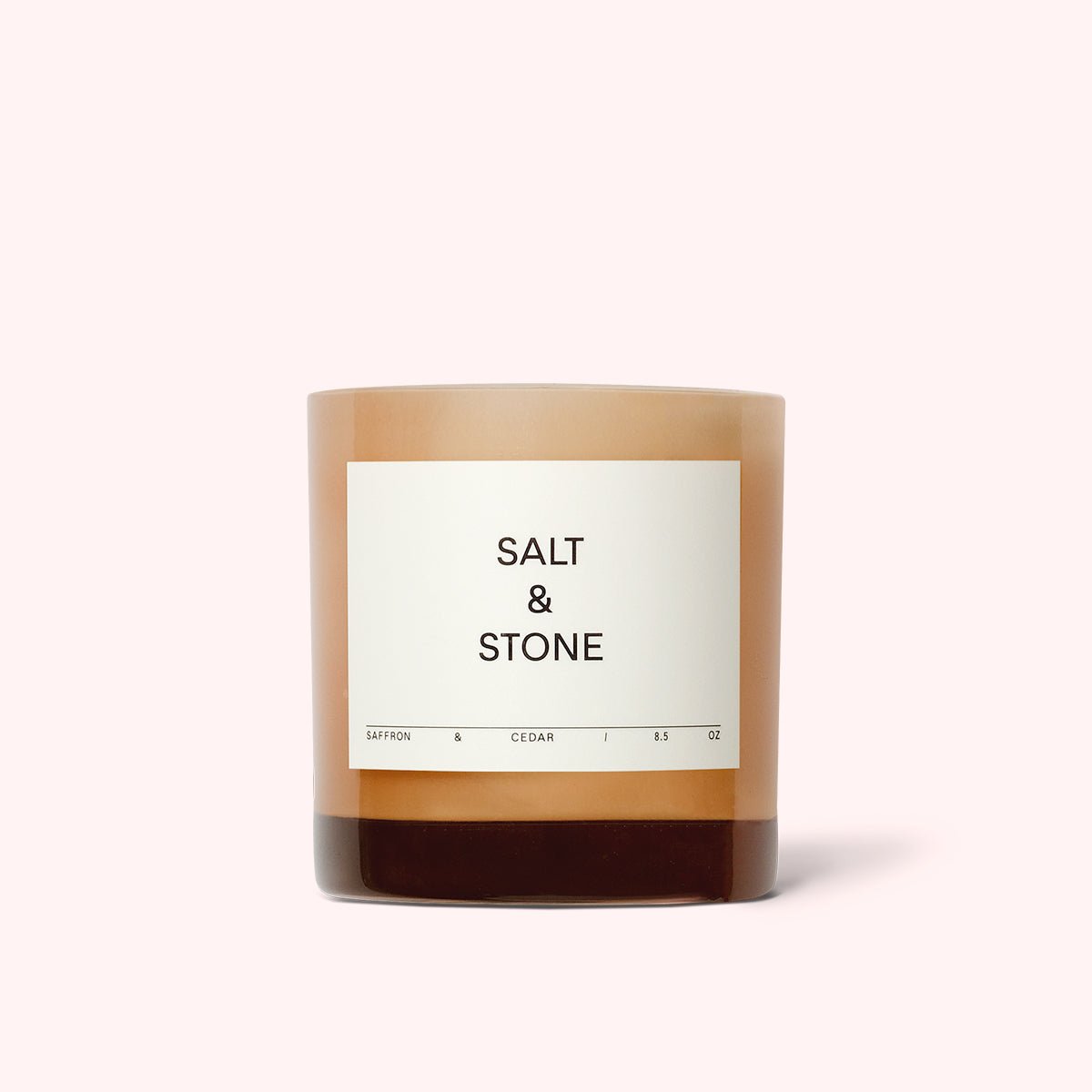 Light pink glass jar filled with a coconut and soy wax candle. The Saffron & Cedar Candle is designed by Salt & Stone and made in Los Angeles, CA.