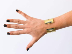 Wide, bold, brass betsy & iya Scania cuff bracelet in the gray, Portland-inspired colorway, pictured on the wrist of a model wearing black nail polish.